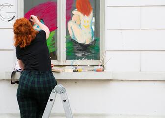 een vrouw die aan het schilderen is op een raam