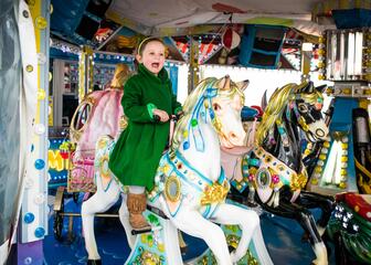 Een meisje geniet van haar ritje op een paardje van de carroussel
