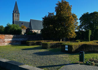 Zonnig zicht op de Sint-Machariuskerk en tuinen.