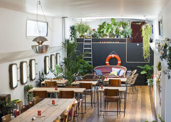 Binnenruimte van schip met tafels, stoelen en planten
