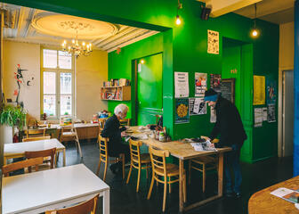 Interieur van buurthuis Trafiek in de Brugse Poort. Twee locals drinken koffie en lezen de krant. 