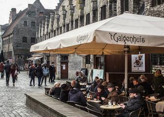 Groot terras van café 't Galgenhuis, met comfortabele rotan stoelen en bescherming door parasols.