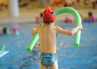 Close-up van kind aan de rand van het zwembad, klaar om te springen.