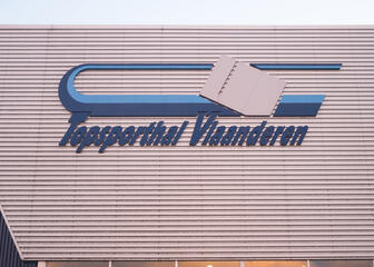 Een close-up van het logo van de Topsporthal Vlaanderen op de gevel. 