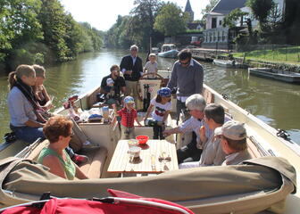 Familie met kinderen op een boot op de Leie buiten de stad
