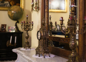 Vintage klok en kandelaars staan voor een spiegel.