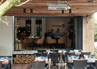 Terras met tafels bij een restaurant - door het raam zie je mensen aan tafel