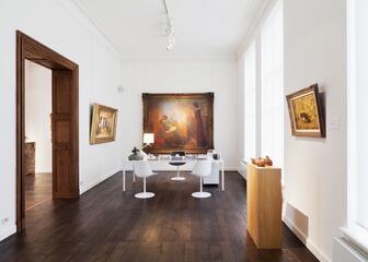 interieur galerij met schilderijen en tafel met stoelen