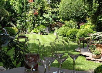Tafel op het terras, gedekt voor twee, met zicht op de groene tuin.