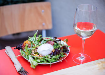 tafel met wijnglas en bord met een slaatje en buffelmozarella
