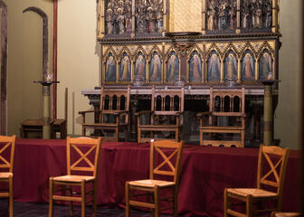 Close-up van het koor met houten stoelen ervoor op een verhoog.