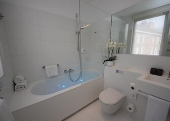 Luxueuze witte badkamer met verlichte badkuip.