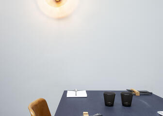 een zwarte gedekte tafel met 2 stoelen tegen een wit met oranje muur