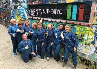 Mensen poseren in plastic overalls en met spuitbussen in de hand voor een zelfgemaakte graffiti in het Graffitistraatje.