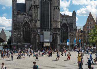 Open plein met zomers geklede wandelaars, op de achtergrond de Sint-Niklaaskerk.