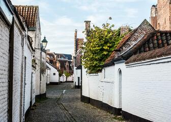 Straatje met kasseien in het Oud Begijnhof, met aan weerskanten witgeschilderde huisjes.