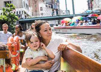Een vrouw en haar kindje zitten op de watertram op de rivier.