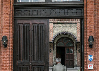 Toegangsdeur naar het museum wordt getoond met een wandelende man in de deuropening.