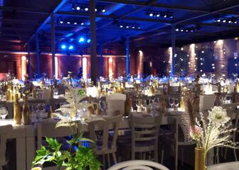 Grote feestzaal met gedekte tafels in blauw-witte verlichting