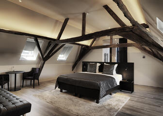 hotelkamer met zwarte elementen, tweepersoonsbed, tafel met stoelen, houten balken