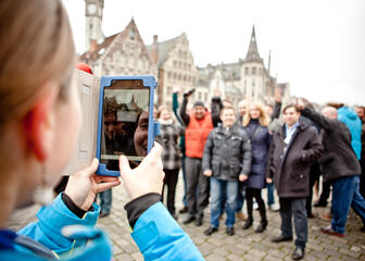 een vrouw die een foto neemt met haar tablet van een groep mensen