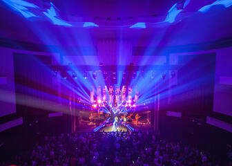 Concert in concertzaal met publiek, felle kleuren vanop het podium