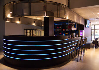 een bar met blauwe verlichting in verwerkt, barstoelen, zitplaatsen