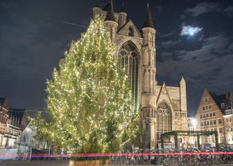 Verlichte kerstboom met Sint-Niklaaskerk op de achtergrond