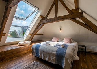 zolderkamer met dubbel bed, houten vloer en links een dakraam