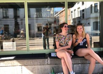 2 lachende, genietende klanten op raambankje met drankje