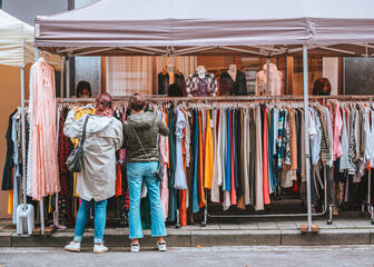 Two ladies picking out clothes during braderie publique