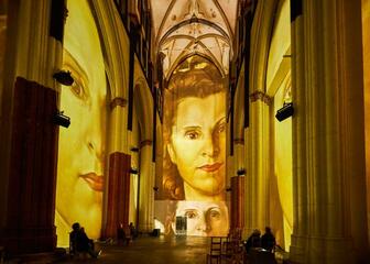 Kleurrijk lichtspektakel met afbeelding van vrouw in de Sint-Niklaaskerk