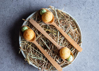 plate with straw and wooden spoons with quail eggs