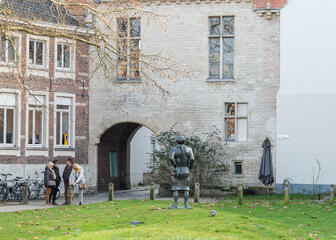 La puerta de Prinsenhof con torretas de ladrillo, en primer plano la estatua del asaltante.