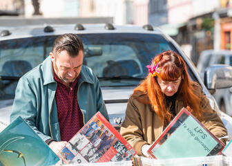 Homme et femme regardant des disques vinyles sur le marché de l'occasion.