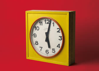 Horloge électrique dans un boîtier en bois peint en jaune provenant d'une des usines UCO de Gand, milieu du 20e siècle.