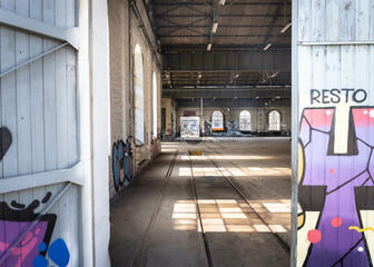 Grote loods met restanten van treinsporen en kleurrijke streetart op de muren
