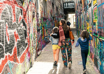 Kinderen en mama wandelen door Graffitistraatje