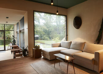 Sala de estar abierta con un gran sofá beige y vistas al jardín