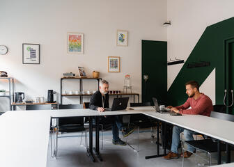 vergaderzaal in U opstelling met 2 mensen aan het werk aan een laptop.