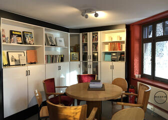 Gemütlicher Raum mit rundem Art-déco-Tisch und Stühlen sowie weißen Schränken mit Büchern