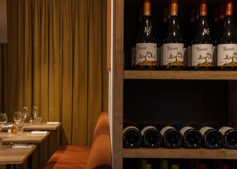 Mesa puesta flanqueada del lado derecho por un armario con botellas de vino 