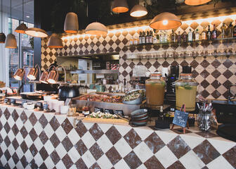 Bar con azulejos marrones y blancos y buffet de comida a la vista