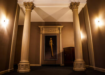 Korridor in Beigetönen mit 2 griechischen Säulen und einem modernen Gemälde