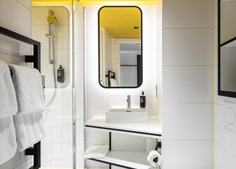 Badkamer met witte betegeling met moderne witte wasbak.