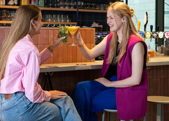 2 vrouwen genieten samen van een drankje achter de bar