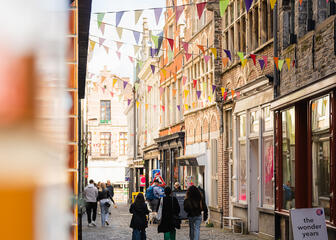 Wandelaars lopen onder de kleurrijke vlagjes in de Serpentstraat in Gent
