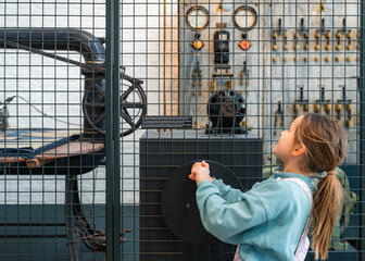 Young girl turns the control wheel of an old machine in the Museum of Industry in Ghent
