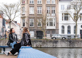 Laura en haar vriendin zitten gezellig te babbelen langs het water in Gent
