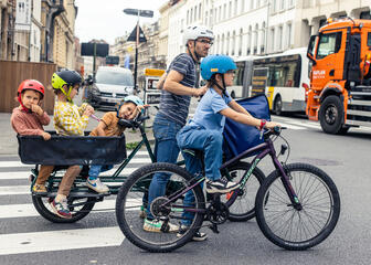 Padre cicla con bicicleta de cola de pulmón con su familia por las calles de Gante
